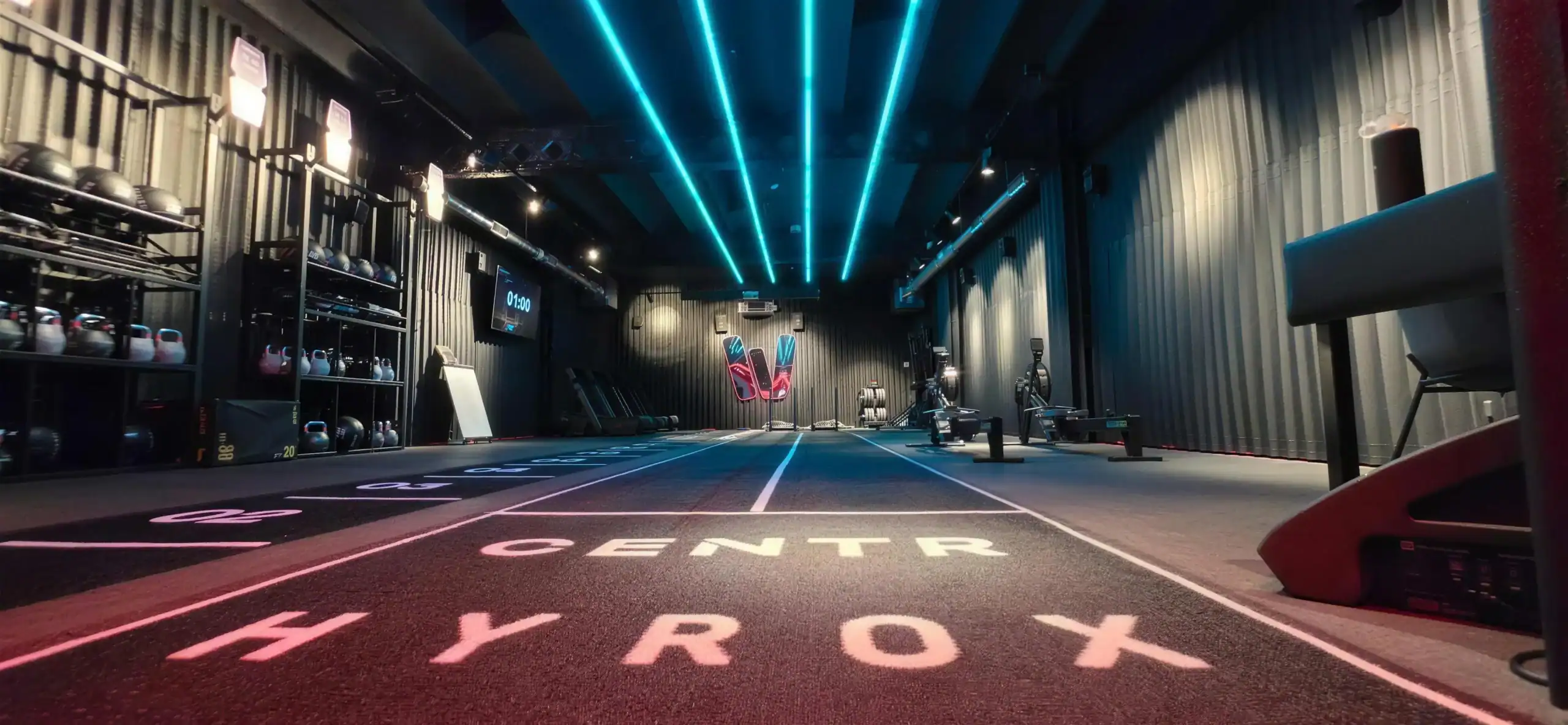 Instalaciones de WHybrid en Barcelona: zona de entrenamiento Hyrox con la pista rotulada en el suelo y luces de neón